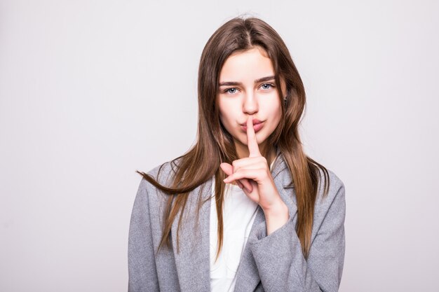 Portrait d'une femme d'affaires avec signe de silence sur fond blanc