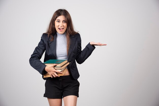 Portrait de femme d'affaires souriante tenant une pile de livres.