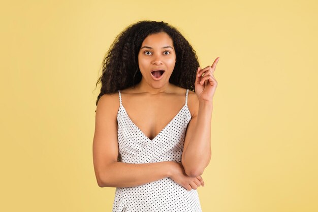 Portrait de femme afro-américaine isolé sur fond de studio jaune avec fond