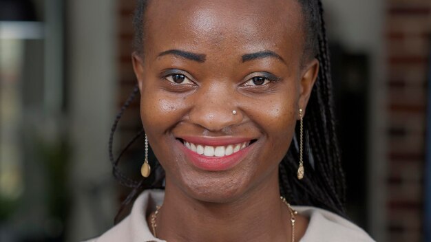 Portrait d'une femme afro-américaine regardant la caméra, maquillée et rouge à lèvres. Jeune adulte se sentant heureux et joyeux, montrant des expressions faciales naturelles positives. Sourire candide.