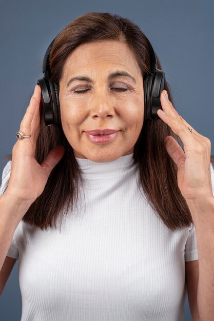 Portrait d'une femme âgée écoutant de la musique avec des écouteurs