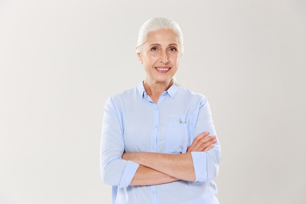 Portrait de femme âgée heureuse debout avec les mains croisées