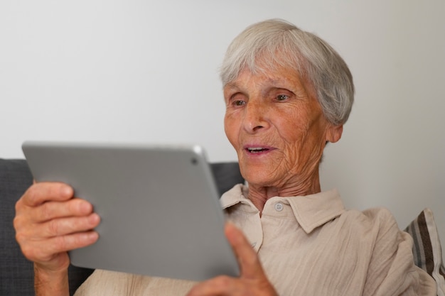 Photo gratuite portrait d'une femme âgée utilisant une tablette à la maison