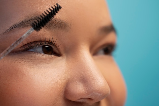 Photo gratuite portrait de femme à l'aide d'une brosse à sourcils