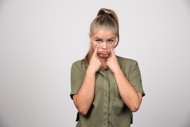 Photo gratuite portrait de femme à l'air si triste sur mur gris.