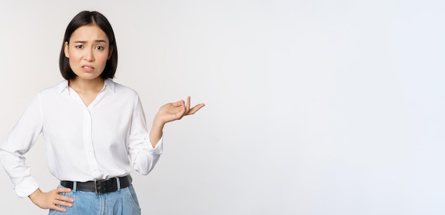 Portrait d'une femme asiatique confuse demandant alors quel est votre problème geste regardant perplexe désemparé et agacé debout sur fond blanc