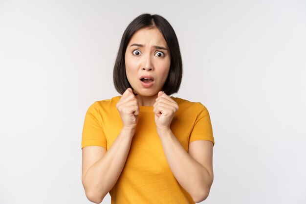 Portrait d'une femme asiatique effrayée secouant de peur l'air terrifié et inquiet debout anxieux sur fond blanc