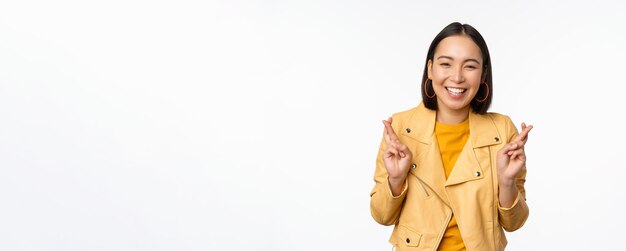 Portrait d'une femme asiatique excitée a l'air plein d'espoir souhaitant prier ou mendier en attendant des nouvelles debout o