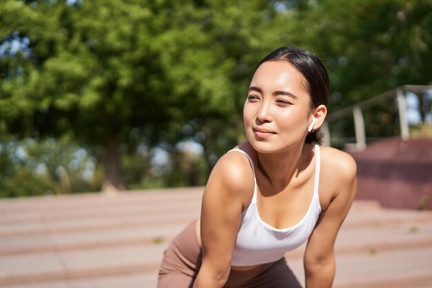 Portrait d'une femme asiatique prenant une pause respirant fortement et haletant après avoir couru un jogger debout et