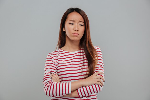 Portrait d'une femme asiatique triste debout avec les bras croisés