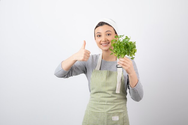 Portrait d'une femme assez mignonne avec faisceau de persil frais montrant un pouce vers le haut