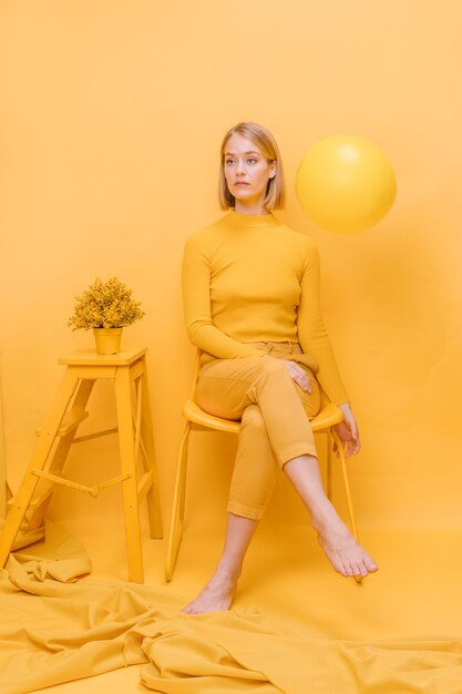 Portrait de femme assise dans une scène jaune