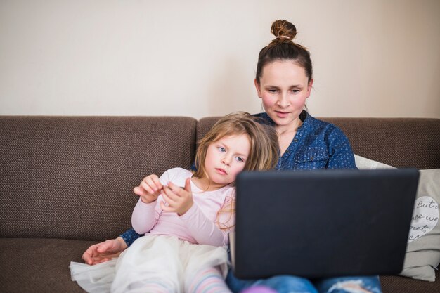 Portrait d&#39;une femme assise avec sa fille à l&#39;aide d&#39;un ordinateur portable