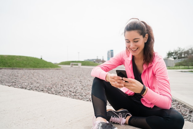 Portrait d'une femme athlétique à l'aide de son téléphone portable lors d'une pause de la formation. Mode de vie sport et santé.