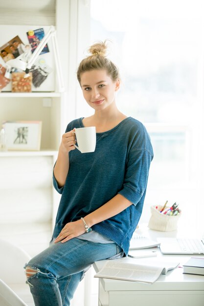 Portrait d&#39;une femme attirante à demi assise à la table