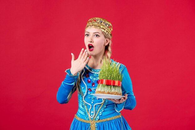 Portrait de femme azérie en costume traditionnel avec semeni studio shot fond rouge concept novruz vacances ethniques printemps