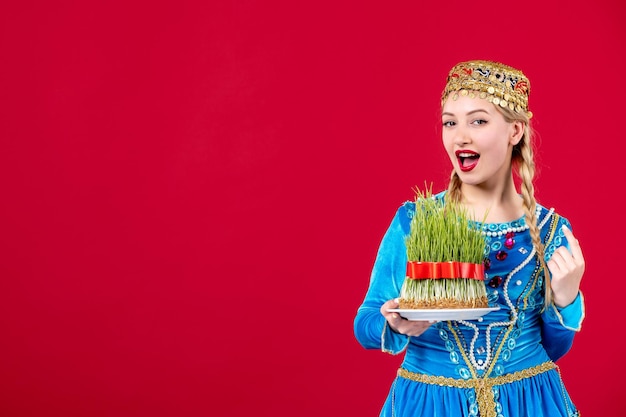 Portrait de femme azérie en costume traditionnel avec semeni vert sur fond rouge concept ethnique novruz couleurs de danseuse de printemps