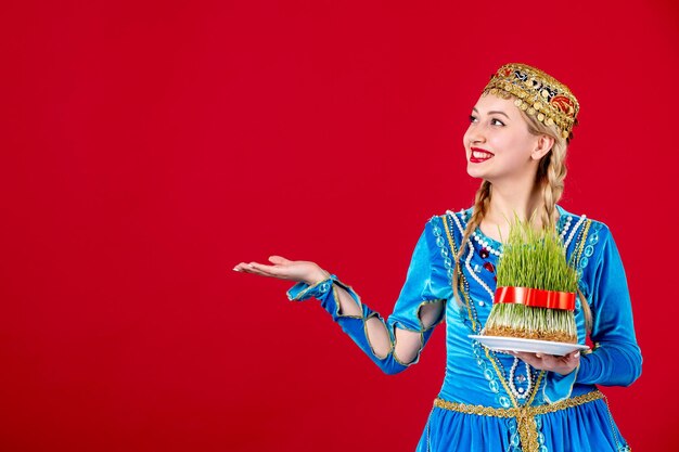 Portrait de femme azérie en costume traditionnel avec semeni vert sur fond rouge concept de printemps novruz