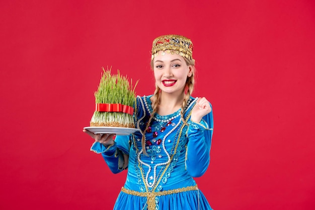 Portrait de femme azérie en costume traditionnel tenant semeni studio tourné fond rouge concept ethnique novruz printemps
