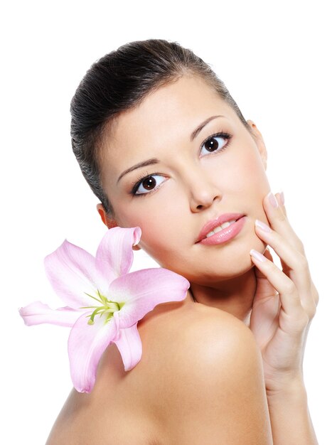 Portrait de femme de beauté avec un lys sur son épaule sur blanc