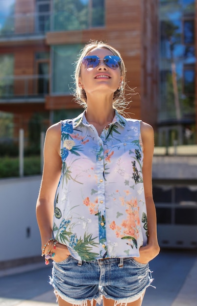 Photo gratuite portrait d'une femme blonde mince en vêtements d'été et lunettes de soleil.