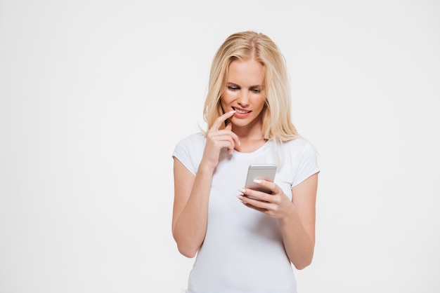 Portrait d'une femme blonde réfléchie à l'aide de téléphone portable