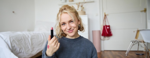 Portrait d'une femme blonde souriante enregistrant une vidéo en direct en ligne sur le contenu des produits de beauté