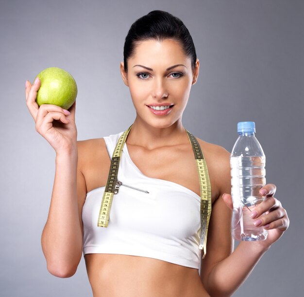 Portrait d'une femme en bonne santé avec pomme et bouteille d'eau. Remise en forme saine et concept de mode de vie alimentaire.