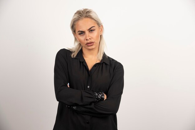 Portrait de femme bouleversée en chemise noire posant sur fond blanc. Photo de haute qualité