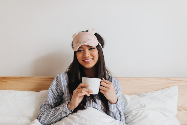 Portrait de femme brune au masque rose pour dormir