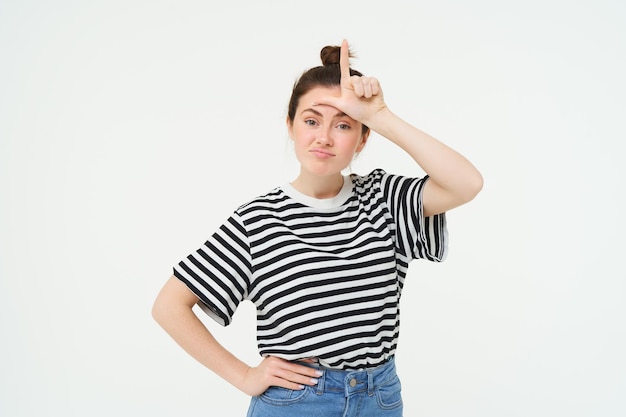 Photo gratuite portrait d'une femme brune montrant une lettre sur le front se moquant de quelqu'un appelant la personne un perdant