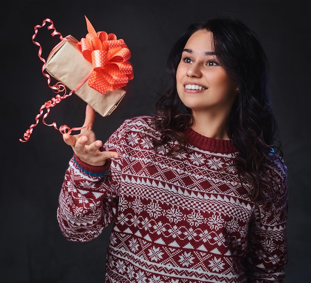 Portrait D'une Femme Brune Souriante Et Festive Aux Longs Cheveux Bouclés, Vêtue D'un Pull Rouge, Tient Des Cadeaux De Noël.