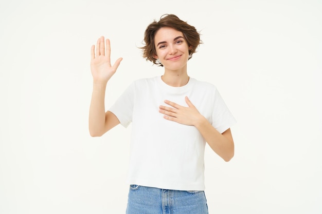 Photo gratuite portrait d'une femme brune souriante lève une paume et met la main sur la poitrine fait une promesse et prête serment