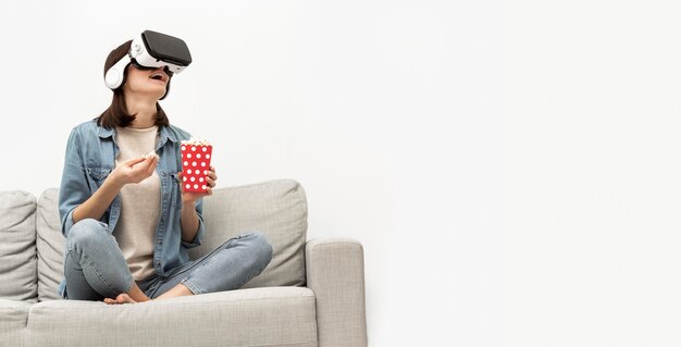 Portrait femme avec casque de réalité virtuelle manger du pop-corn