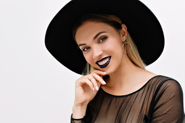 Portrait de femme charmante souriante avec rouge à lèvres noir et chapeau noir