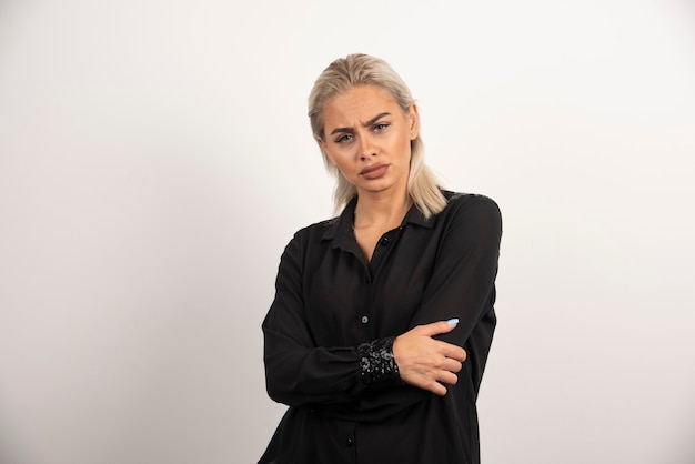 Portrait de femme en chemise noire posant sur fond blanc. Photo de haute qualité