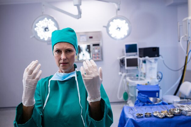 Portrait de femme chirurgien portant des gants chirurgicaux en salle d'opération