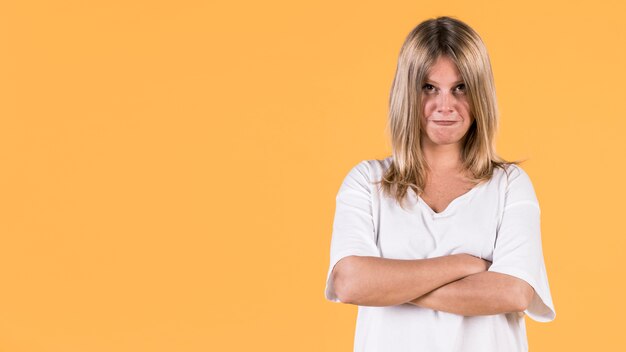 Portrait de femme en colère, debout sur un fond jaune