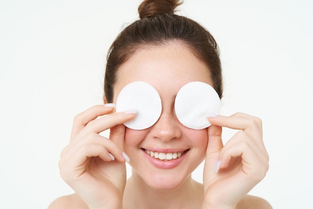 Photo gratuite portrait d'une femme couvrant ses yeux avec des tampons de coton nettoyant sa peau après le maquillage à l'aide quotidienne