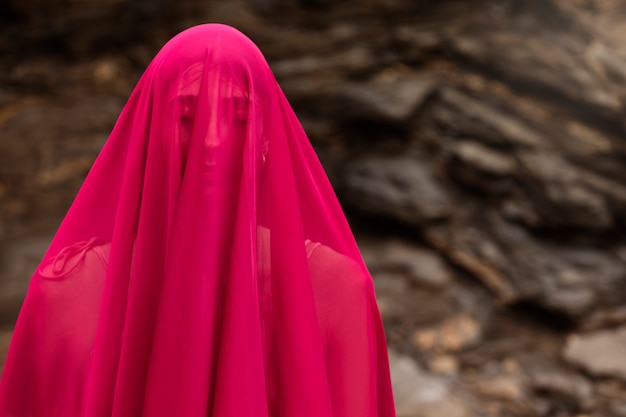 Portrait de femme couvrant son visage avec un voile à la plage