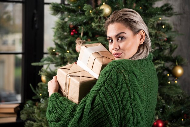 Portrait d'une femme dans un pull vert tenant des cadeaux