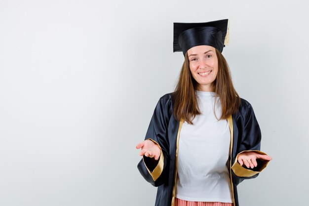 Portrait de femme diplômée répandre les mains à la caméra dans des vêtements décontractés, uniforme et à la joyeuse vue de face