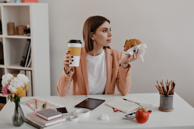 Portrait de femme entrepreneur au déjeuner au bureau. Travailleur de manger un hamburger sur le lieu de travail.