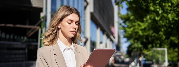 Portrait d'une femme d'entreprise lit des actualités sur sa tablette numérique alors qu'elle se rend au bureau