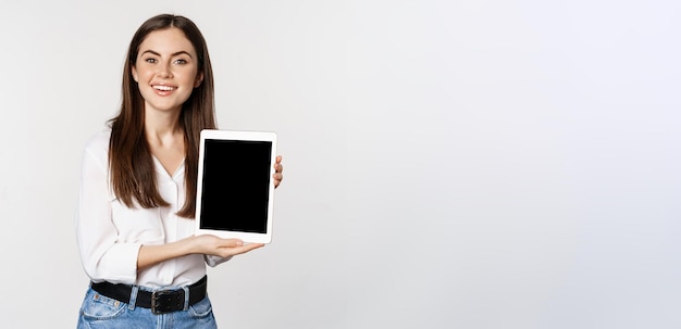 Portrait de femme d'entreprise montrant l'écran de la tablette démontrant le site Web de l'entreprise debout sur blanc