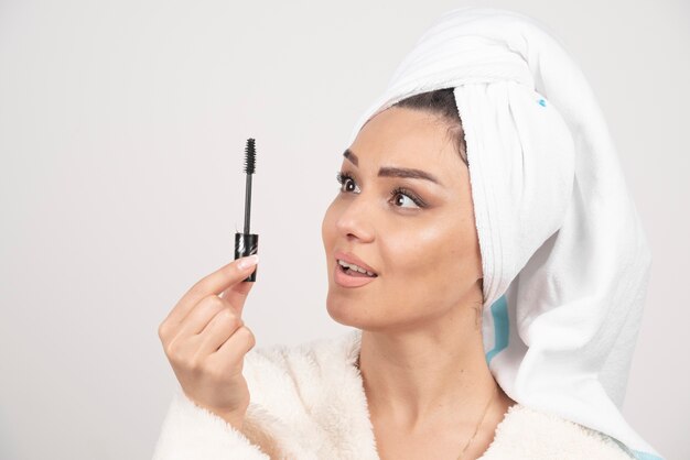 Portrait de femme enveloppée dans une serviette blanche à la recherche de mascara.