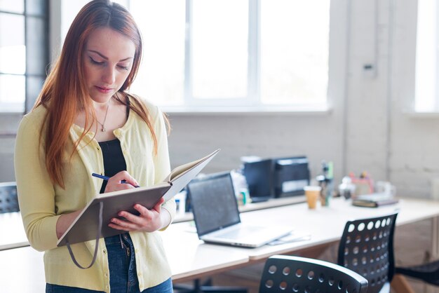 Portrait de femme faisant des notes dans le bloc-notes sur le lieu de travail