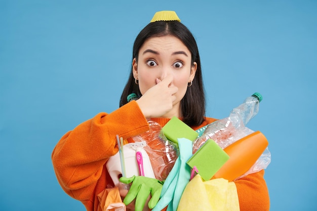 Photo gratuite portrait de femme ferme son nez de dégoût tenant des ordures puantes en plastique sale et bo vide