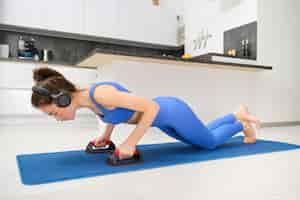 Photo gratuite portrait d'une femme de fitness en leggings faisant des pompes avec de l'équipement sportif à l'entraînement à domicile