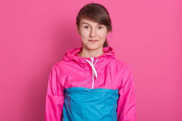 Portrait de femme fitness posant après avoir travaillé dans une salle de sport, portant des vêtements de sport bleu et rose, regardant directement la caméra, ayant les cheveux noirs